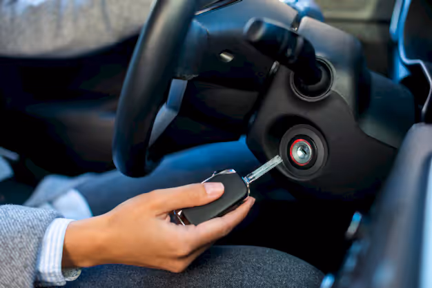 Driver holding a car key fob next to a push button ignition